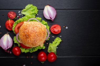 Sebzeli Dana burgerler. Siyah dokulu arka plan üzerine marul, domates ve baharat ile yatıyor. Üstten Görünüm