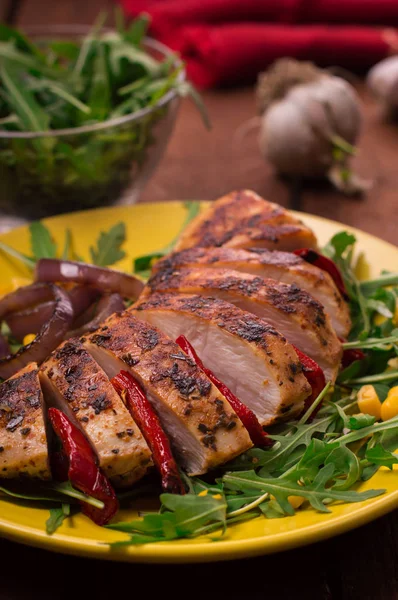 Gegrillte Hühnerbrust mit grünem Salat aus Rucola und Gemüse auf einem gelben Teller. rustikalen hölzernen Hintergrund. Ansicht von oben — Stockfoto