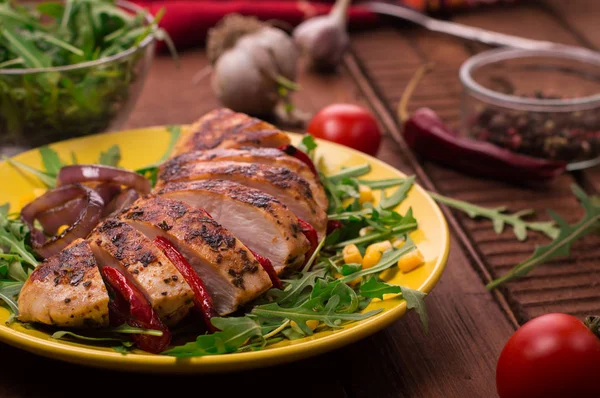 ルッコラと黄色のプレートで野菜からサラダと焼き鶏の胸肉。木製の素朴な背景。トップ ビュー — ストック写真