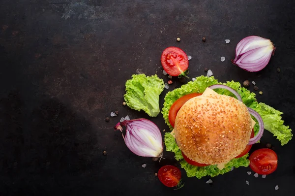 Hamburgare på nötkött med grönsaker. Ligger på svart texturerat bakgrund med sallad, tomater och kryddor. Ovanifrån — Stockfoto