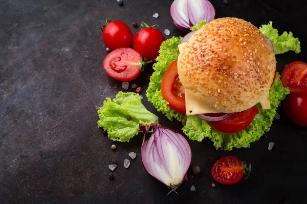 Hamburgare på nötkött med grönsaker. Ligger på svart texturerat bakgrund med sallad, tomater och kryddor. Ovanifrån — Stockfoto