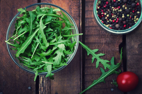 Fresh arugula leaves, rucola. Wooden rustic background. Top view.
