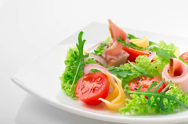 Fresh salad with tomatoes, arugula, cheese and ham on the white plate and white background — Stock Photo, Image