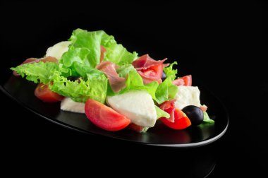 Parlak siyah bir zemin üzerine taze lezzetli salata