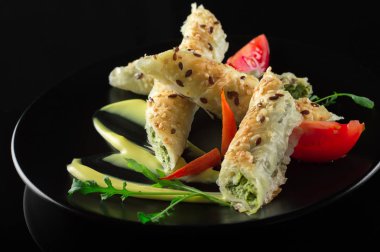 Ispanak ve peynirli bir siyah plaka ve siyah arka plan üzerinde doldurma puf böreği