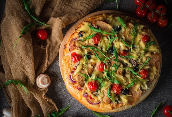 Pizza con pollo, rucola, formaggio e cipolle su tavolo rustico in legno. Vista dall'alto — Foto Stock