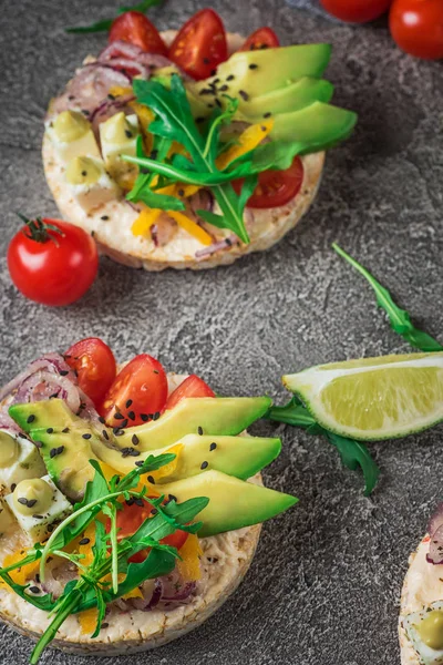 Bruschetta con pomodoro, avocado, erbe aromatiche e rucola. Sfondo rustico. Vista dall'alto — Foto Stock