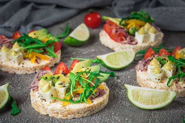 Bruschetta with tomato, avocado, herbs and arugula. Rustic background. Top view