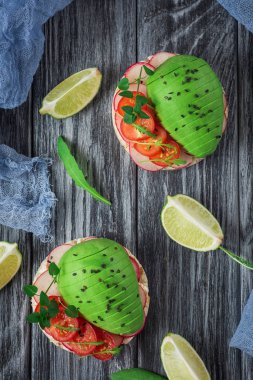 Bruschetta domates, avokado, otlar ve roka ile. Rustik arka plan. Üstten Görünüm