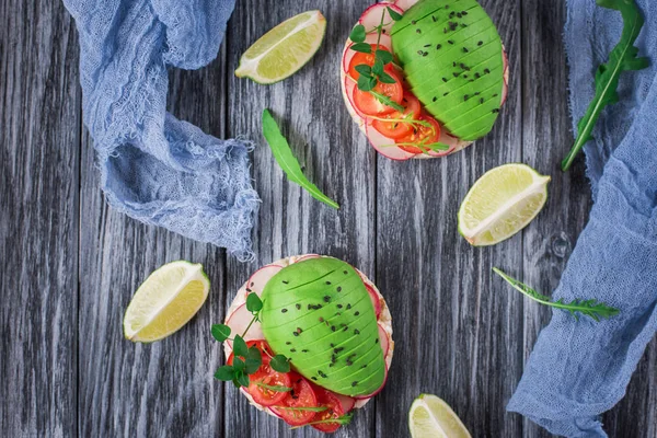 Bruschetta con pomodoro, avocado, erbe aromatiche e rucola. Sfondo rustico. Vista dall'alto — Foto Stock