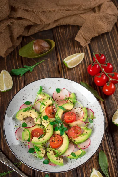 Ensalada de verduras con aguacate, rúcula, rábano, lima y aceite de oliva. Alimento saludable dietético. Fondo rústico de madera. Vista superior — Foto de Stock