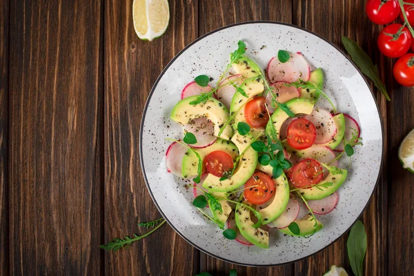 Insalata di verdure con avocado, rucola, ravanello, lime e olio d'oliva. Alimenti dietetici sani. Sfondo rustico in legno. Vista dall'alto — Foto Stock