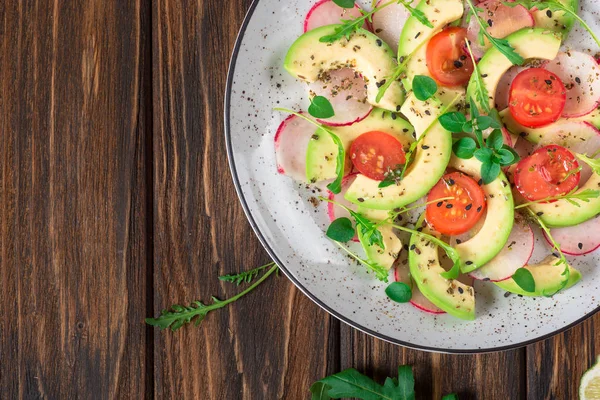 Grönsakssallad med avokado, ruccola, rädisor, lime och olivolja. Kost hälsosam mat. Trä rustik bakgrund. Ovanifrån — Stockfoto