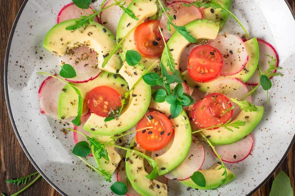 Zeleninový salát s avokádem, rukolou, ředkvičkami, vápno a olivový olej. Dietní zdravé jídlo. Dřevěný rustikální pozadí. Pohled shora — Stock fotografie