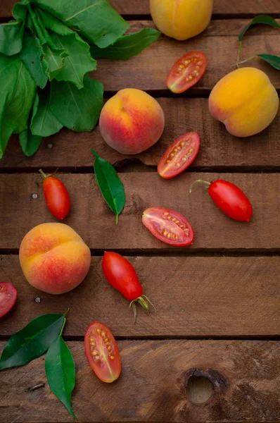 Rijpe perziken en tomaten op houten achtergrond. Bovenaanzicht — Stockfoto