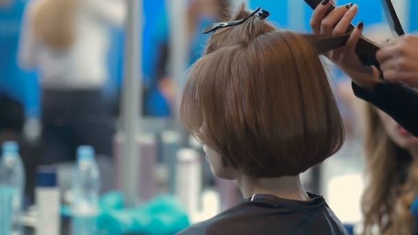 Female model whith basic bob getting hair straightened by hairdresser closeup on the backstage of fashion week — Stock Video