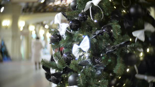 Bolas negras brillantes y mate y lazo blanco. Año Nuevo y abstracto fondo borroso centro comercial con decoraciones de árboles de Navidad . — Vídeo de stock