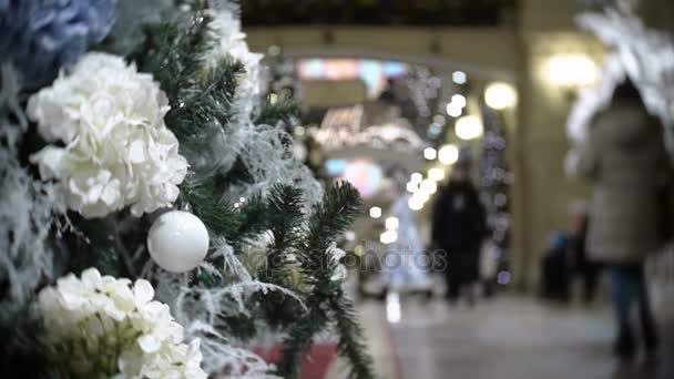 Vista deslizante de bolas blancas y flores. Año Nuevo y abstracto fondo borroso centro comercial con decoraciones de árboles de Navidad . — Vídeos de Stock