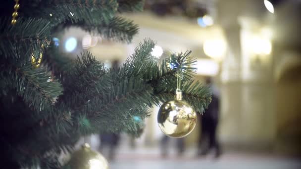 Slider view of small golden mirror ball. New Years and abstract blurred shopping mall background with Christmas tree decorations. — Stock Video