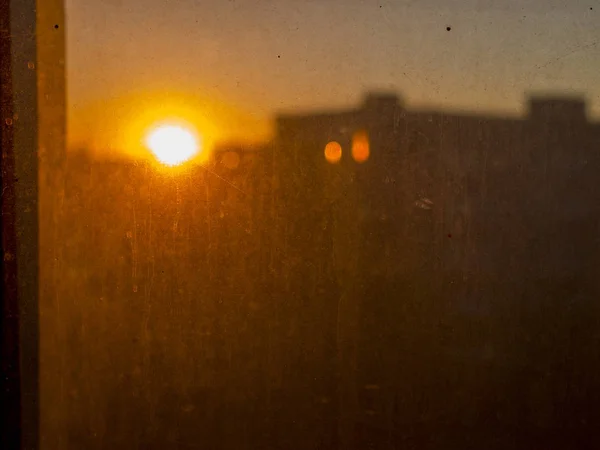 在尘土飞扬、肮脏的玻璃后面可以看到红色的日落 — 图库照片