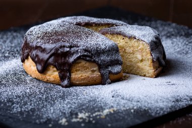 Siyah arka plan üzerine pudra şekeri serpilir ev yapımı çikolatalı kek