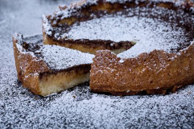 Siyah arka plan üzerine kesilmiş parça ile pudra şekeri ile ev yapımı çikolatalı kek