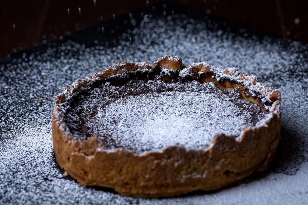 Siyah arka plan üzerine kesilmiş parça ile pudra şekeri ile ev yapımı çikolatalı kek — Stok fotoğraf