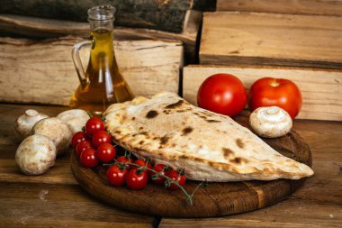  alzone pizza malzemelerle ahşap masa üzerinde