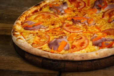 Jambon, domates ve biber ahşap arka plan üzerinde pizza