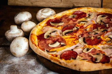 Salam ve sosis ve mantar malzemelerle ahşap arka plan üzerinde pizza