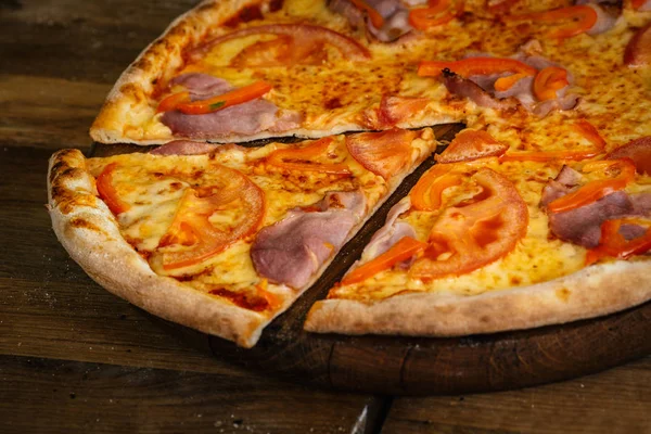 Pizza com presunto, tomate e pimenta sobre fundo de madeira — Fotografia de Stock