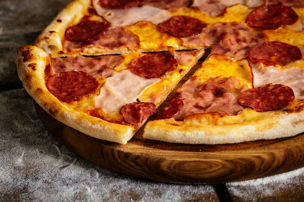 Pizza com presunto e salsichas sobre fundo de madeira — Fotografia de Stock