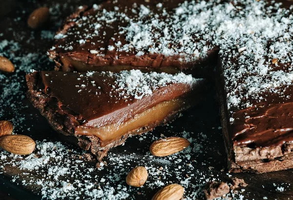 Ahşap oyun tahtası bademli çikolata tuzlu karamel tart — Stok fotoğraf