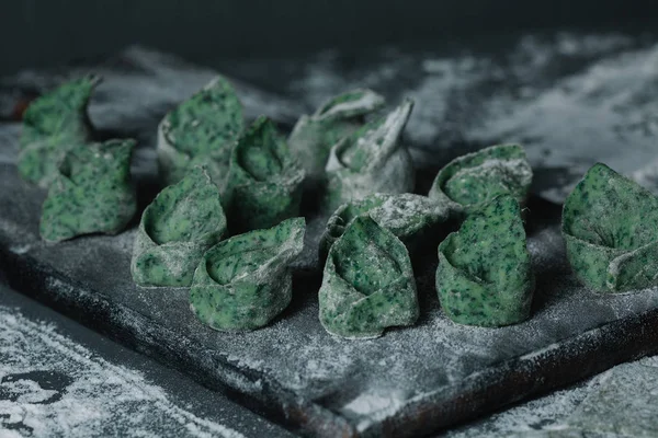 Natürmort ısırgan tortellini ve koyu arka plan üzerinde taze ısırgan otu ile
