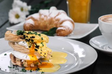 Haşlanmış yumurta sandviç kahvaltı kruvasan, meyve suyu, kahve ve koyu ahşap arka plan üzerinde papatya