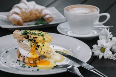 Haşlanmış yumurta sandviç kahvaltı kruvasan, meyve suyu, kahve ve koyu ahşap arka plan üzerinde papatya