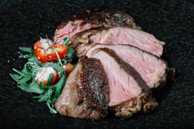 Izgara dana biftek salata ile koyu arka plan üzerine dilimlenmiş