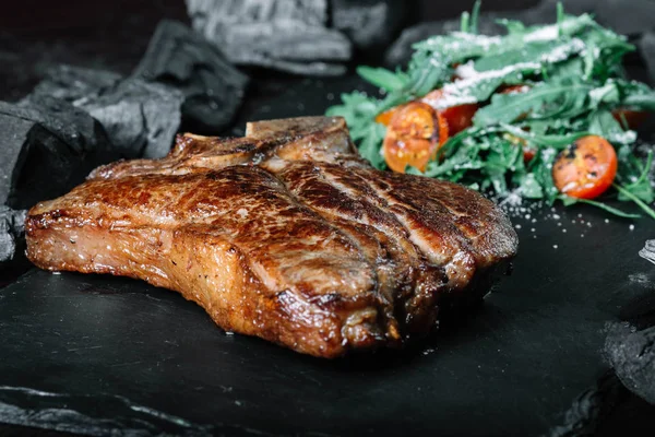 Grilovaný T-bone steak s rajčaty a kořením na tmavém pozadí — Stock fotografie