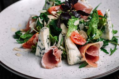 Jambon ve koyu ahşap zemin üzerine mavi peynir ile yeşil salata