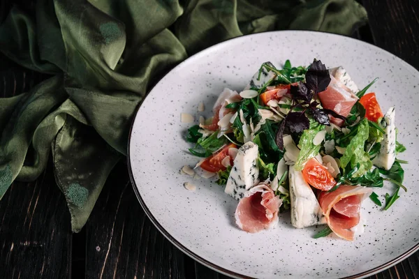 Zöld saláta, kék sajt és sonka és tálalva szövet a sötét fából készült háttér — Stock Fotó