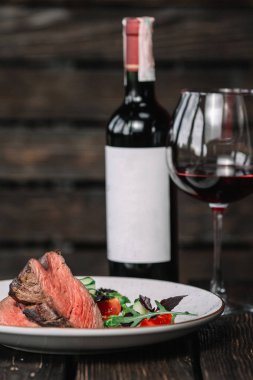 Şişe ve koyu ahşap arka plan üzerinde kırmızı şarap ile ızgara biftek
