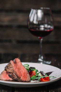 Koyu ahşap arka plan üzerinde kırmızı şarap ile ızgara biftek