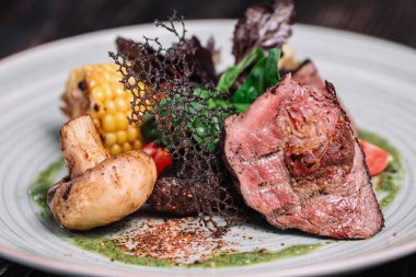 Koyu ahşap zemin üzerine sebzeli ızgara biftek