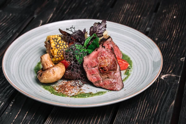 Koyu ahşap zemin üzerine sebzeli ızgara biftek