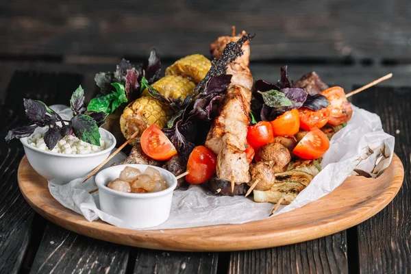 Cracklings ve brynza koyu ahşap arka plan üzerinde ahşap bir gemide ile çeşitli lezzetli ızgara et sebze ile servis