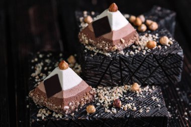 İki ahşap arka plan üzerine bir piramit şeklinde üç çikolatalı mousse kek