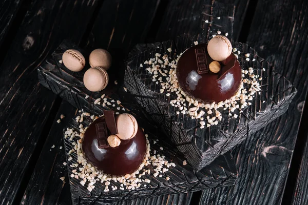 French chocolate mousse cake on wood background. Dessert decorated with macaroon, nut and piece of chocolate bar