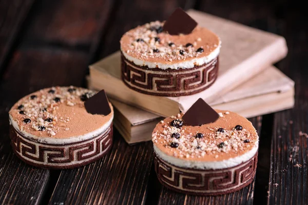 Üç özgün kek çikolata ve ahşap zemin üzerine kitaplar ile dekore edilmiş