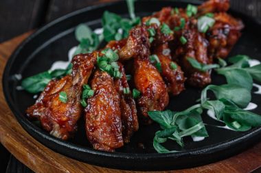 Tavada tavuk kanatları koyu ahşap arka plan üzerinde kesme tahtası üzerinde