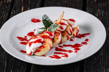 ottage krep ekşi krema ve koyu ahşap arka plan üzerinde beyaz tabakta reçel ile